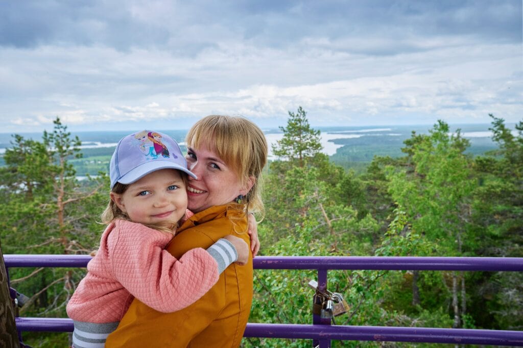 Retkeilyä. Kuvassa äiti ja tytär halaa Vuokatinvaaran näköalatornin huipulla.