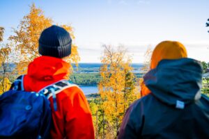 Retkeilykuvaa. Kaksi henkilöä katsoo ruskamaisemaa Vuokatinvaaralla.